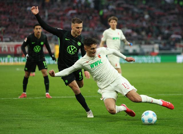 Augsburg's Dimitrios Giannoulis and Wolfsburg's Kilian Fischer in action at the WWK-Arena, 15. March 2025.