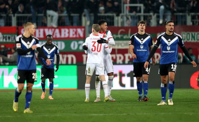 Happy Augsburg players surrounded by disappointed HSV players.