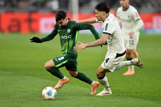 Mohamed Amoura (VfL Wolfsburg) and Kevin Diks (Borussia Mönchengladbach) contest for possession, 13. December 2025.