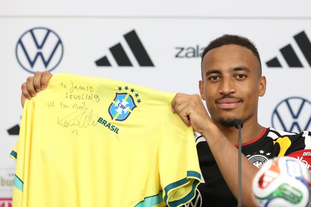 Jamie Leweling holding up a Brazil kit signed by Ronaldo.