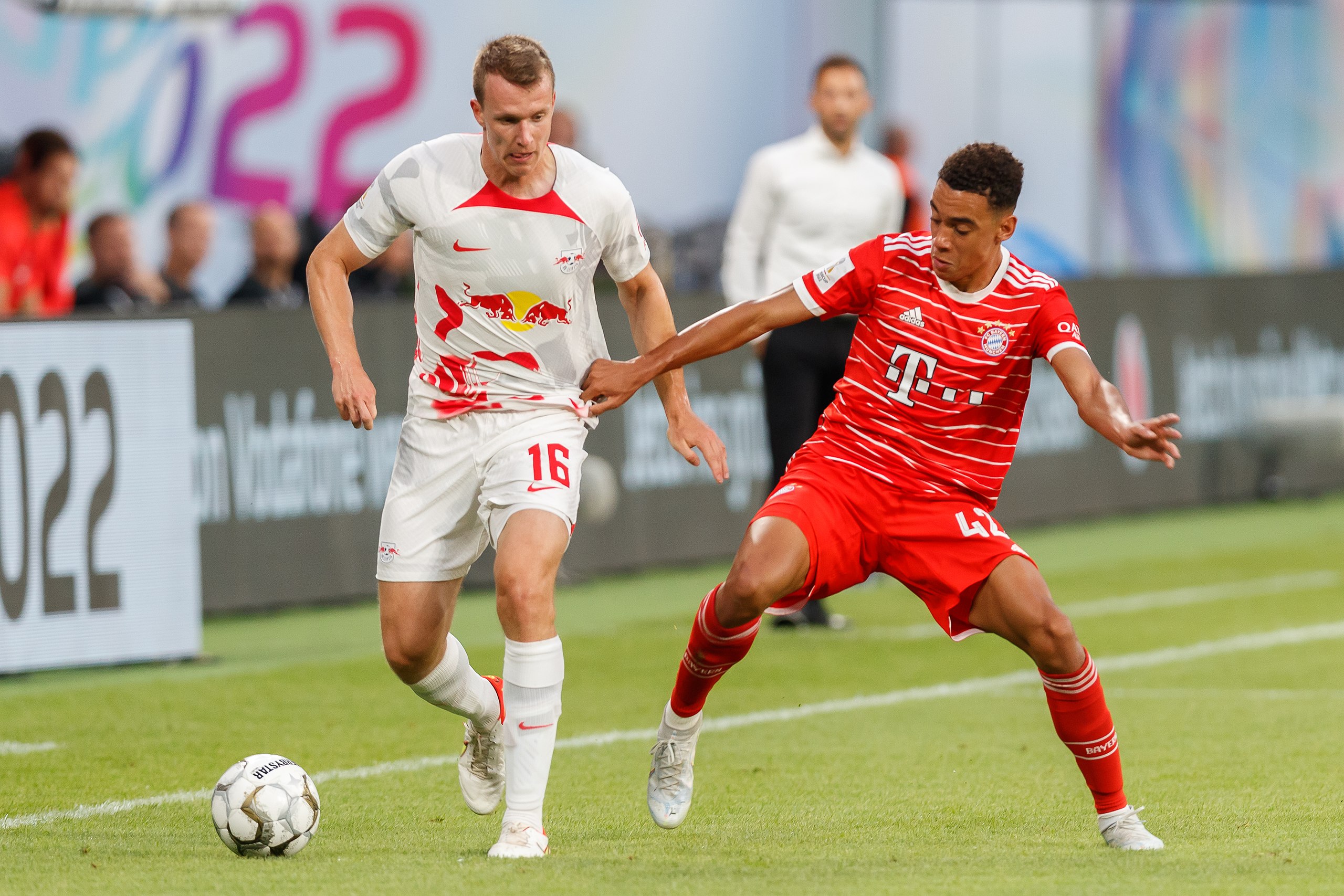  Jamal Musiala, a Bayern Munich player, is attempting to get past an Arsenal player during a soccer match.